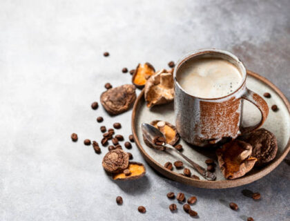 Mushroom coffee, a ceramic cup, mushrooms and coffee beans on stone concrete background. New Superfood Trend.