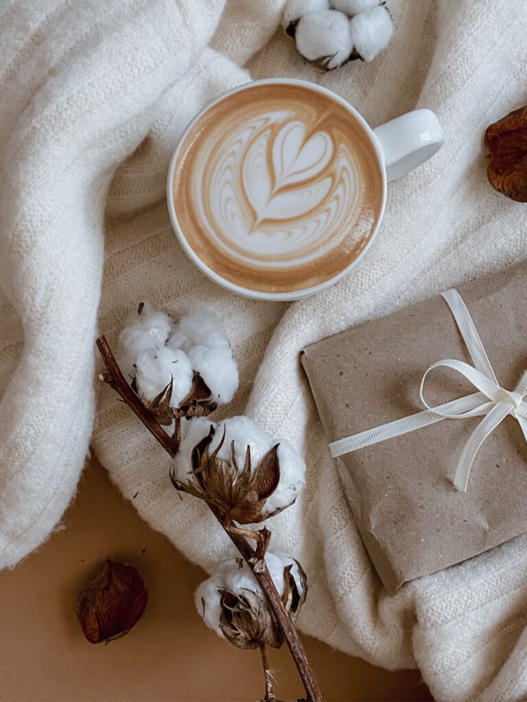 Latte amongst cotton roses and blankets