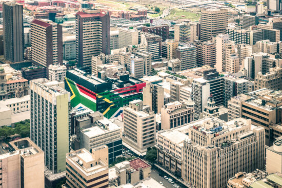 Close up detail of skyscrapers the business district of Johannesburg - Aerial view of modern buildings of the skyline in South Africa biggest city with southafrican flag painted on structure walls