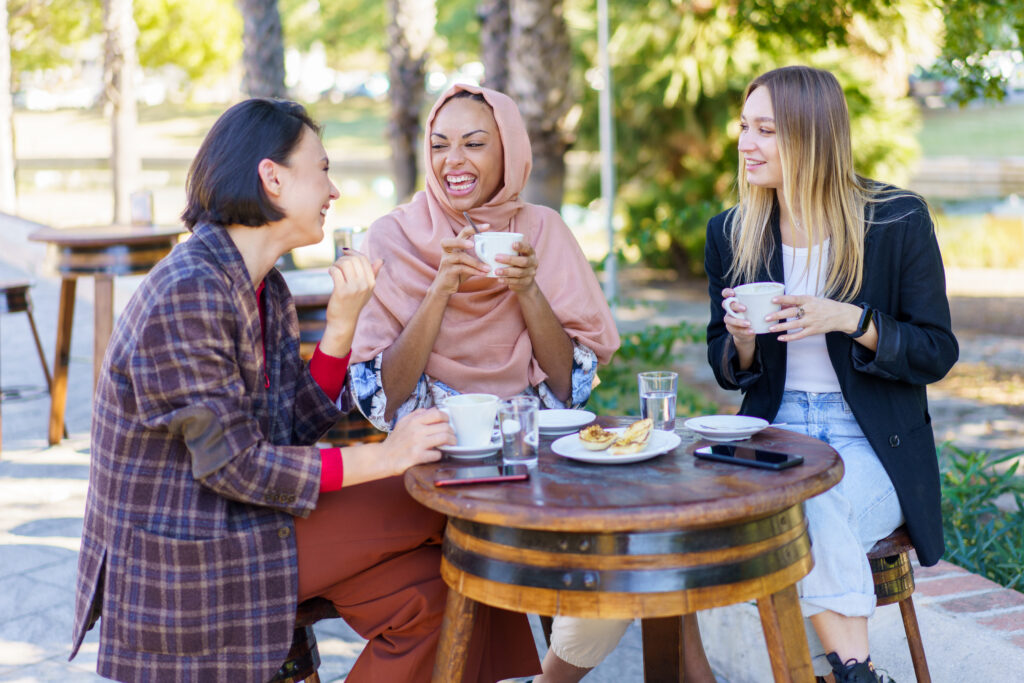 Group of smiling female friends looking at each other while having coffee break