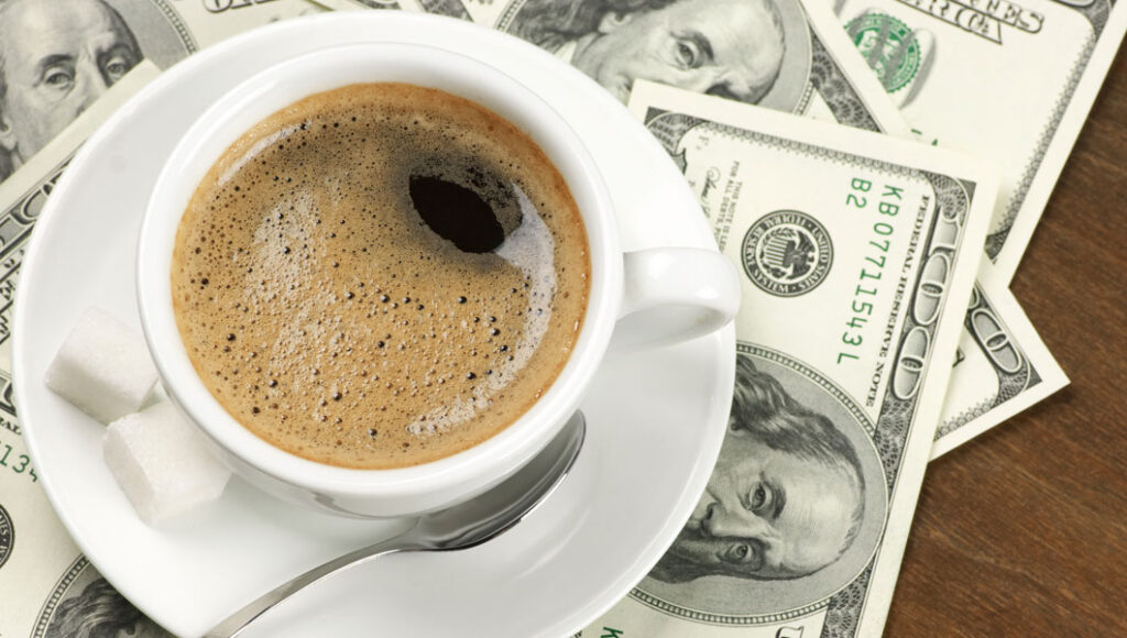 a cup of coffee on top of one hundred dollare bills