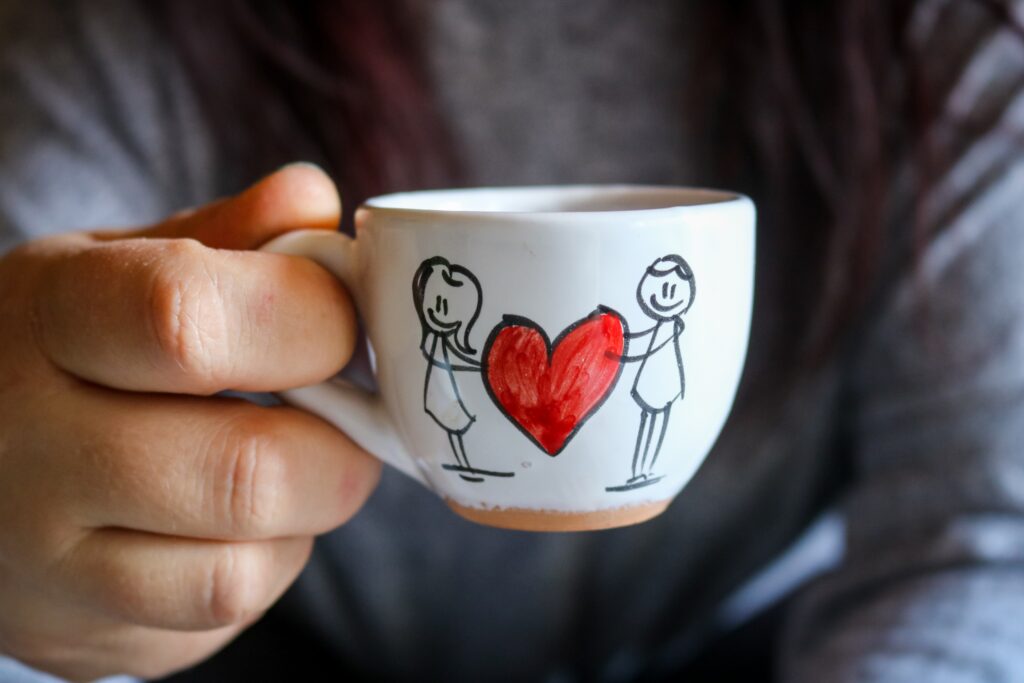 a man holding a cup with two stick figures holding a heart 