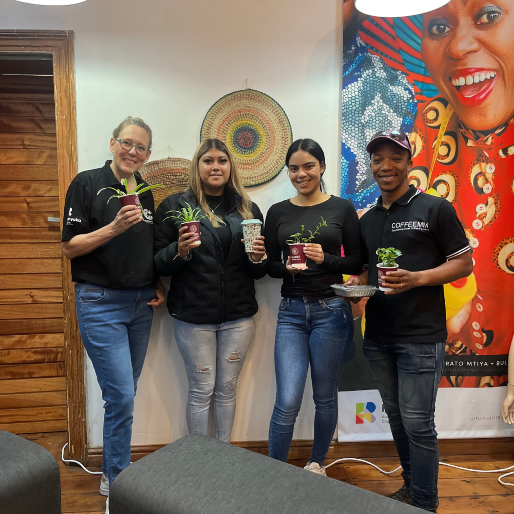 the daily java team and the coffeemm team holding a small plant 