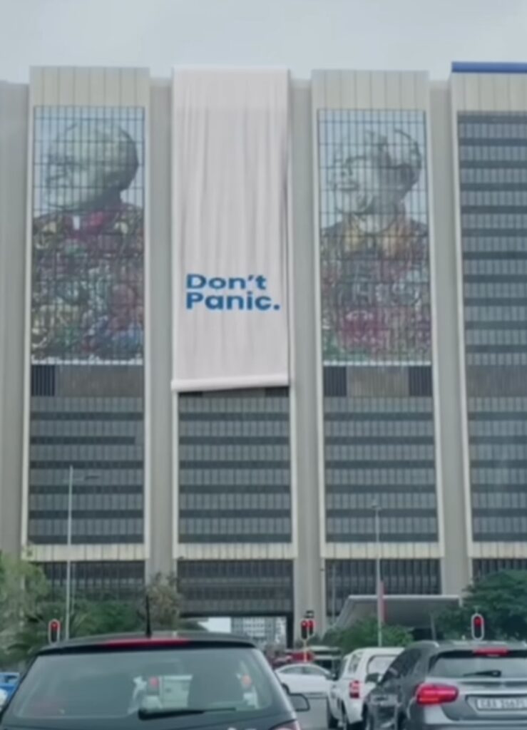 scroll hanging down building saying "Don't Panic" 