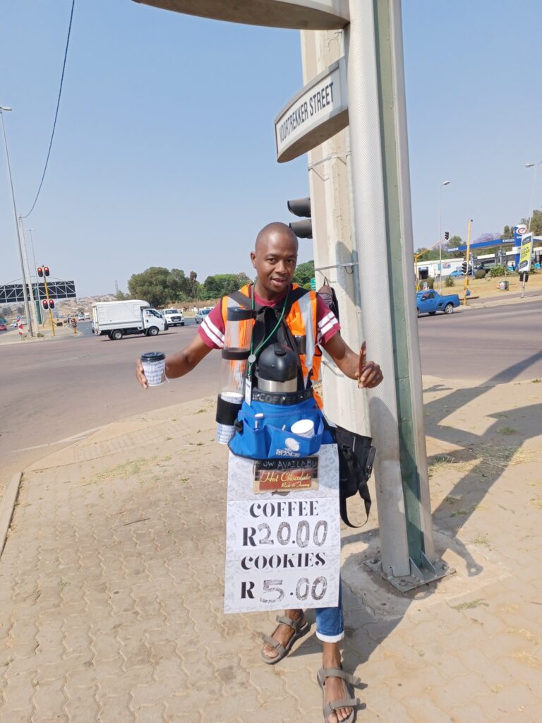 man standing at robot with sign that says coffee for R20 and cookies for R5