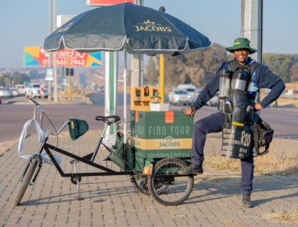 man standing next to a coffee bicycle